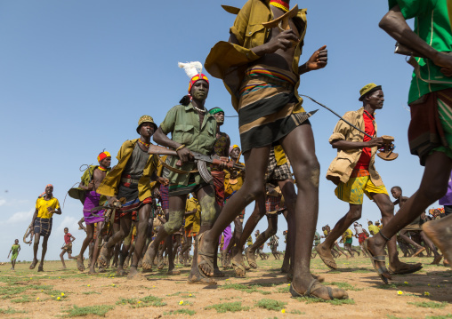Men running in line with weapons during the proud ox ceremony in the Dassanech tribe, Turkana County, Omorate, Ethiopia