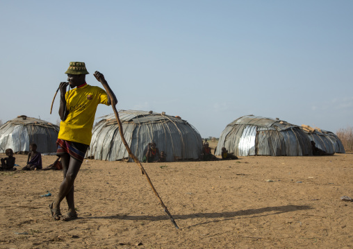Dassanech tribe man resting on his long stick in a village, Omo valley, Omorate, Ethiopia
