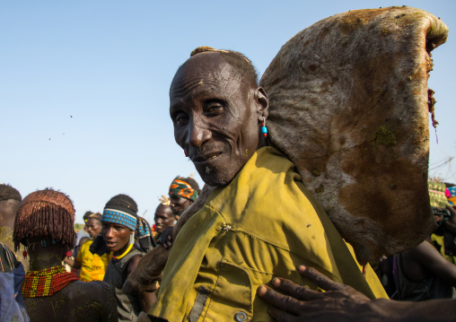 Old man carrying a big piece of cow meat during the proud ox ceremony in Dassanech tribe, Turkana County, Omorate, Ethiopia
