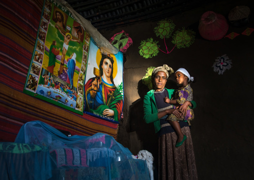 Gurage mother with her daughter inside her traditional house decorated with doilies and chirstian posters on the walls, Gurage Zone, Butajira, Ethiopia