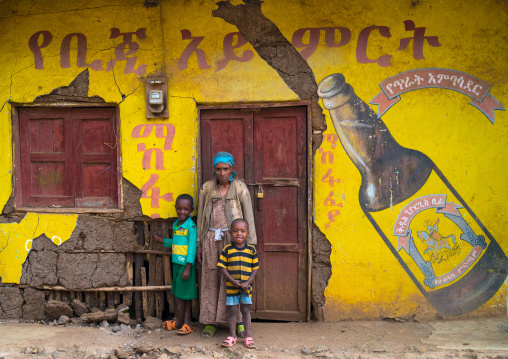 Ethiopian family standing in front of an old beer advertising painted on a wall, Omo valley, Jinka, Ethiopia
