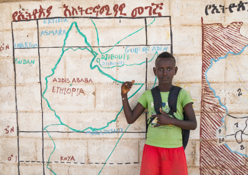 Nyangatom tribe boy in front of a school mural depicting the map of east africa, Omo valley, Kangate, Ethiopia