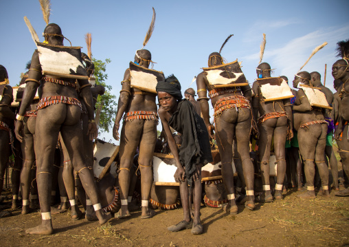 Child boy in front of Bodi tribe fat men during Kael ceremony, Omo valley, Hana Mursi, Ethiopia