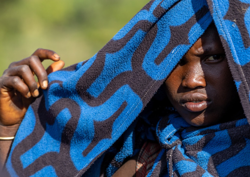 Suri tribe girl protecting her head from the sun with her blanket, Omo valley, Kibish, Ethiopia