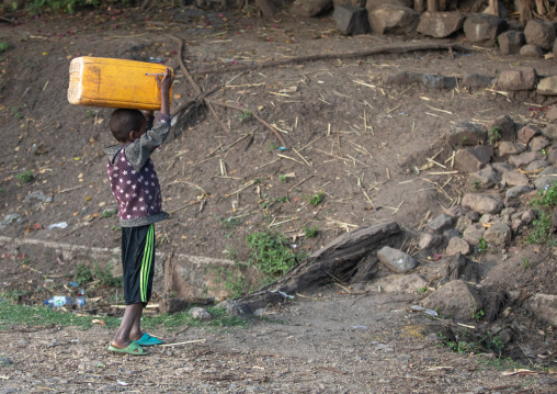 Ethiopian boy carrying water jerrican on his head, Amhara region, Senbete, Ethiopia