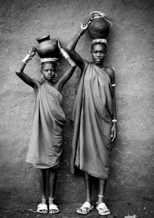 Black And White Portrait Of Bodi Tribe Women Carrying Jars Of Milk On Their Head, Hana Mursi Village, Omo Valley, Ethiopia