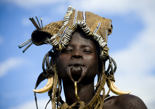 Portrait Of A Smiling Mursi Tribe Woman With Warthog Tusks As Earrings And Enlarged Lip, Omo Valley, Ethiopia