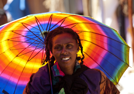 Woman under a rainbow umbrella portrait, Ethiopia
