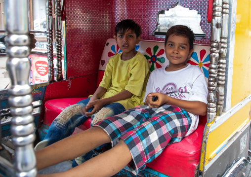 Two indian boys sit in a rickshaw, Rajasthan, Jodhpur, India