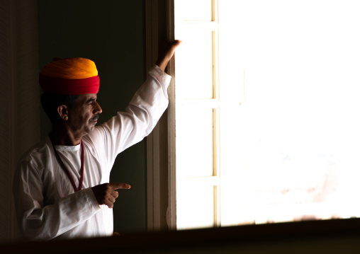 Portrait of a rajasthani man in traditional clothing looking thru a window, Rajasthan, Jodhpur, India