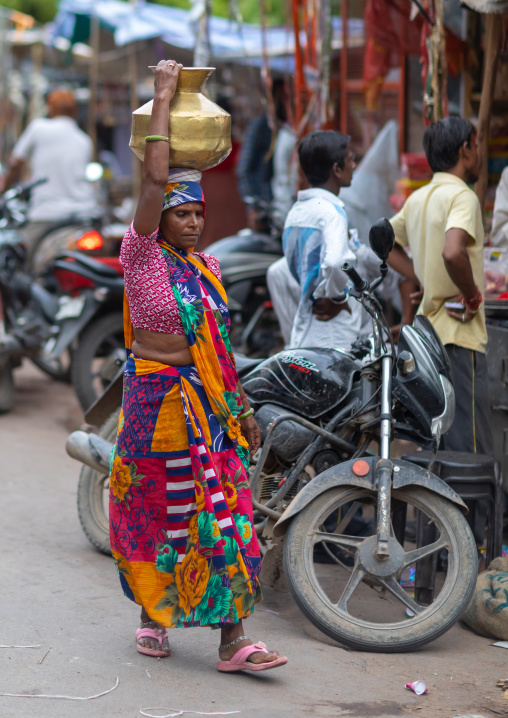 Indian woman carrying a jug on her head in the street, Rajasthan, Bundi, India