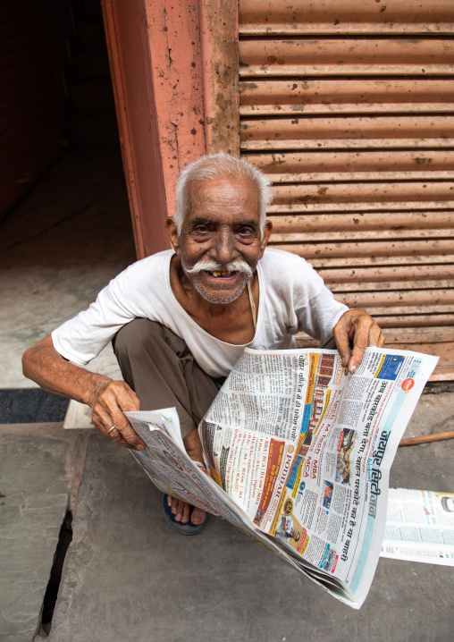 Smiling indian man reading the newspaper in the street, Rajasthan, Jaipur, India