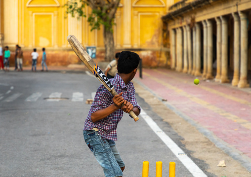 Young boy holding a cricket bat and playing in the street, Rajasthan, Jaipur, India