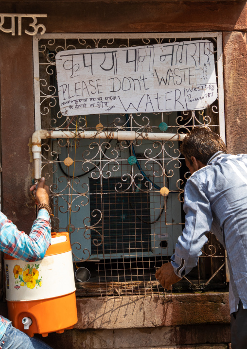 Indian men collecting water in the street during ther heat wave, Rajasthan, Osian, India
