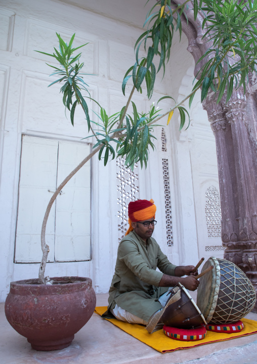Portrait of a rajasthani man in traditional clothing playing drum in a temple, Rajasthan, Jodhpur, India
