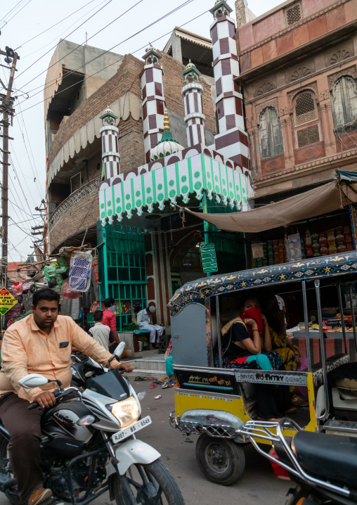 Indian riders ride motorbikes in front of a mosque, Rajasthan, Bikaner, India