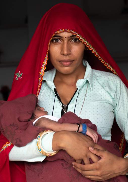 Portrait of a rajasthani woman with her baby in the arms, Rajasthan, Baswa, India