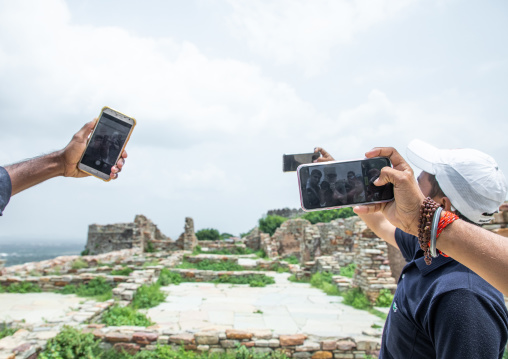 Tourists taking selfies in front of the ruined rana kumbha palace inside Chittorgarh fort complex, Rajasthan, Chittorgarh, India