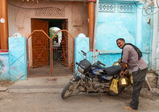 Indian man delivering fresh milk with his motorbike, Rajasthan, Bundi, India