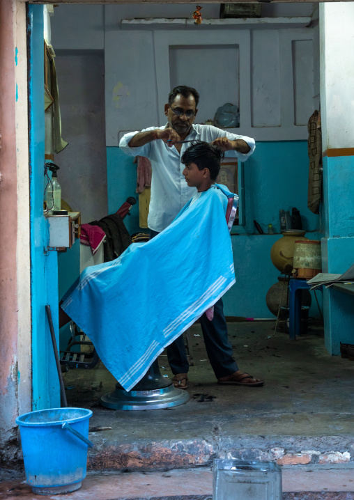 Hairdresser cutting young man's hair on the streets, Rajasthan, Jodhpur, India