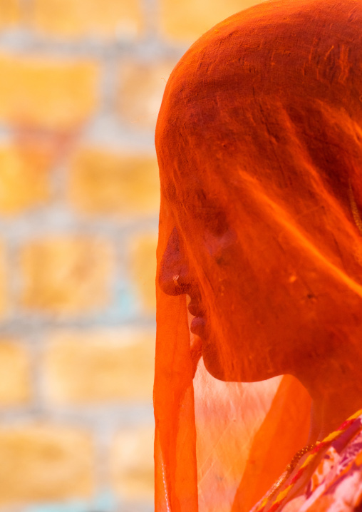 Portrait of a rajasthani woman hidding her face under a orange sari, Rajasthan, Jaisalmer, India