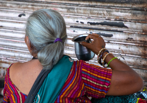 Indian woman drinking in the street during ther heat wave, Rajasthan, Jaipur, India