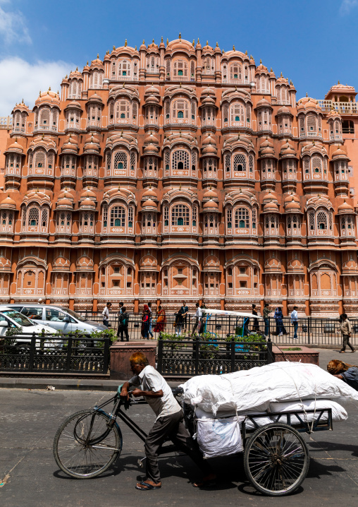Indian man pushing a loaded bicycle in front of front of the hawa mahal, Rajasthan, Jaipur, India