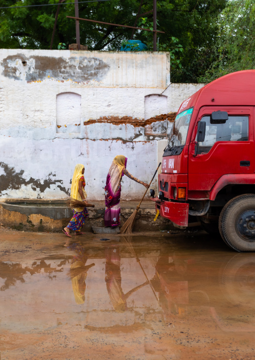 Indian women walking in the street during the monsoon, Rajasthan, Nawalgarh, India