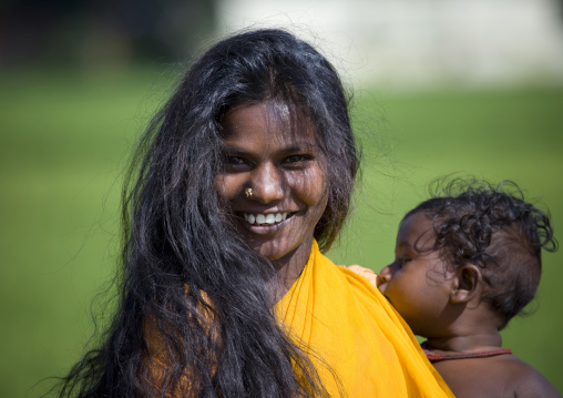 Young Smiling Mother With Long Black Hair Holding Her Baby In Her Arms, Periyar, India