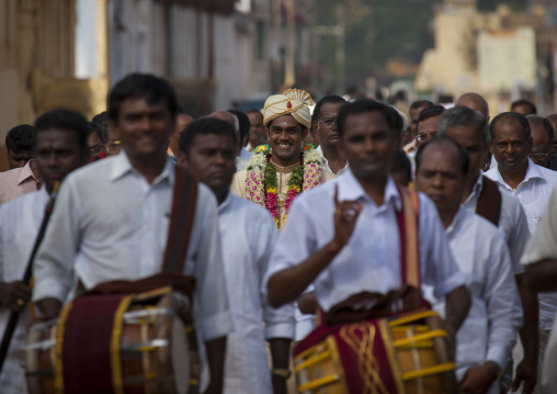 Young Groom Dressed For The Ceremony With Flower Garland Surrounded By Men  In White In Procession For The Wedding, Kanadukathan Chettinad, India