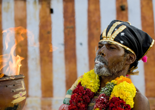 Man Covered By Ashes With Peaks In His Tongue, Traditional Clothing And A Flower Garland Holding A Jar On Fire During Fire Walking Ceremony, Madurai, South India