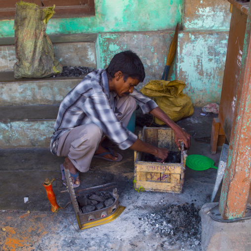 Squatting Man Filling A Coal Iron At The Bottom Of Some Steps Pondicherry, India