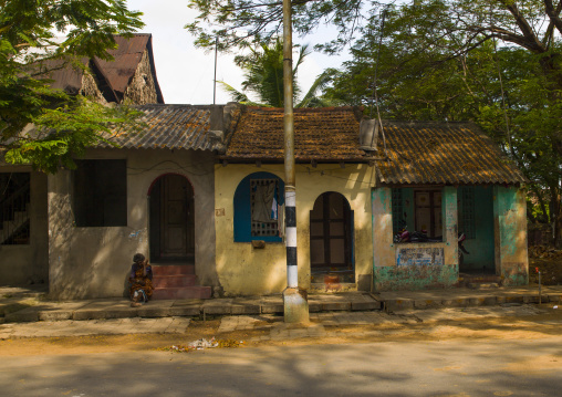 Old Woman Sitting On Doorstep Of A Old Decrepit House In The Street Of Pondicherry, India