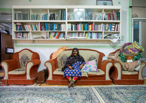 a bandari woman wearing a traditional mask called the burqa sitting in a modern house, Qeshm Island, Salakh, Iran