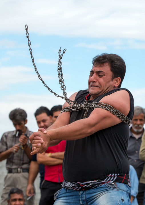 a strongman struggles to break free of chains at the panjshambe bazar thursday market, Hormozgan, Minab, Iran