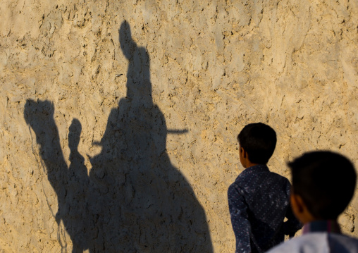 shadow on an adobe wall of the groom riding his camel during a wedding ceremony, Qeshm Island, Salakh, Iran