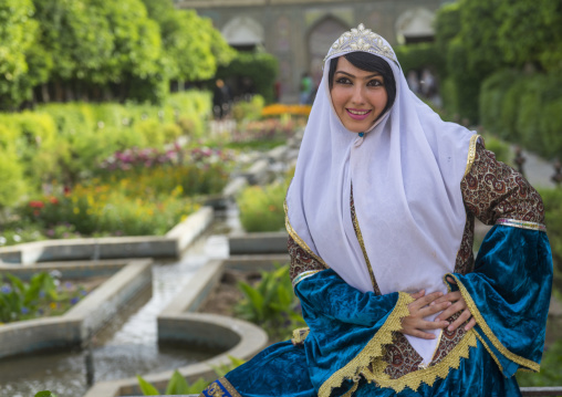 Young woman pausing in narenjestan garden in traditional clothing, Fars province, Shiraz, Iran