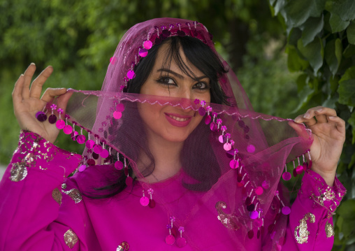 Young woman pausing in narenjestan garden in traditional clothing, Fars province, Shiraz, Iran