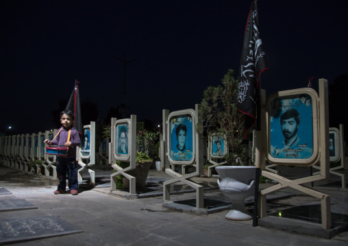 Portrait of an iranian shiite boy playing drum in the Rose garden of martyrs cemetery, Isfahan Province, Isfahan, Iran