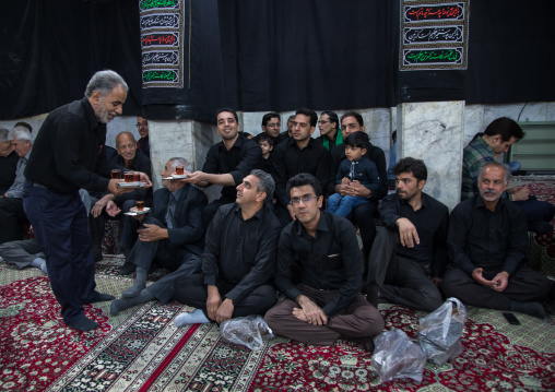 Iranian shiite muslim mourners drinking tea during Muharram inside a hosseinieh, Yazd Province, Yazd, Iran