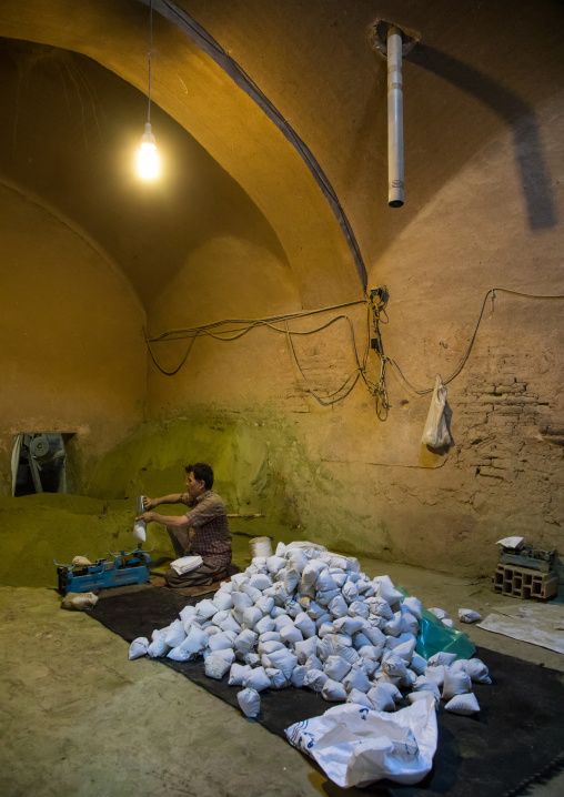 Afghani worker packing henna bags in a traditional mill, Yazd Province, Yazd, Iran