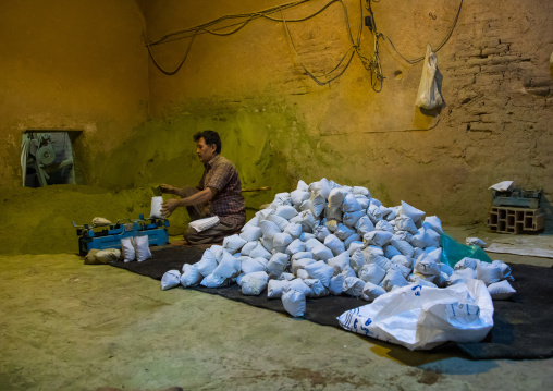 Afghani worker packing henna bags in a traditional mill, Yazd Province, Yazd, Iran