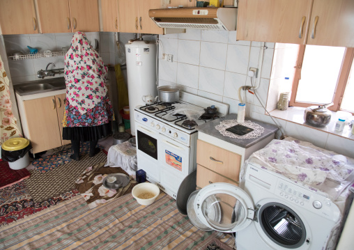 Iranian woman wearing traditional floreal chador in her kitchen, Natanz County, Abyaneh, Iran