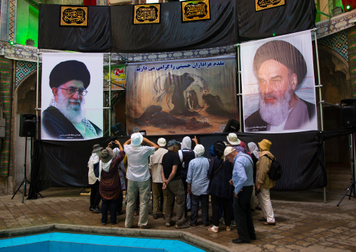 Tourists In Front Of Khameini And Khomeini Posters in the bazar, Isfahan Province, Kashan, Iran