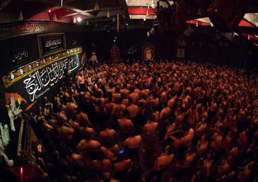 Iranian shiite muslim mourners from the mad of Hussein community chanting and self-flagellating during Muharram in their hosseinieh, Isfahan Province, Kashan, Iran