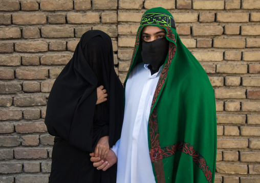 Portrait of iranian shiite muslim couple with their faces hidden by a veil mourning Imam Hussein on Tasua during the Chehel Manbar ceremony one day before Ashura, Lorestan Province, Khorramab