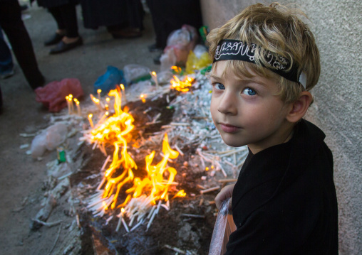 Iranian boy lights candles during Chehel Manbar ceremony on Tasua to commemorate the martyrdom anniversary of hussein, Lorestan Province, Khorramabad, Iran