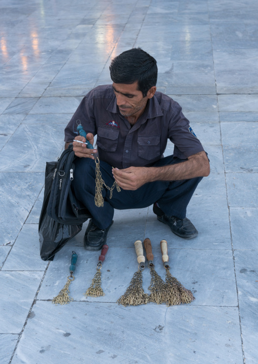 Man selling iron chains for children in Fatima al-Masumeh shrine during Muharram, Central County, Qom, Iran