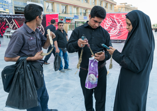 Shiite couple buying iron chains for children in Fatima al-Masumeh shrine during Muharram, Central County, Qom, Iran