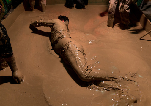 An iranian shiite muslim man rolls over in a mud pond as he takes part in the Kharrah Mali ritual during the Ashura ceremony, Lorestan Province, Khorramabad, Iran